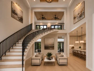 Double-height living room with a sweeping staircase, oak ceiling, and warm neutral furnishings